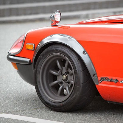 Close-up of a red classic car with chrome details on a road.