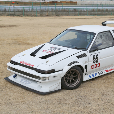 White race car with various sponsor logos on a dirt track