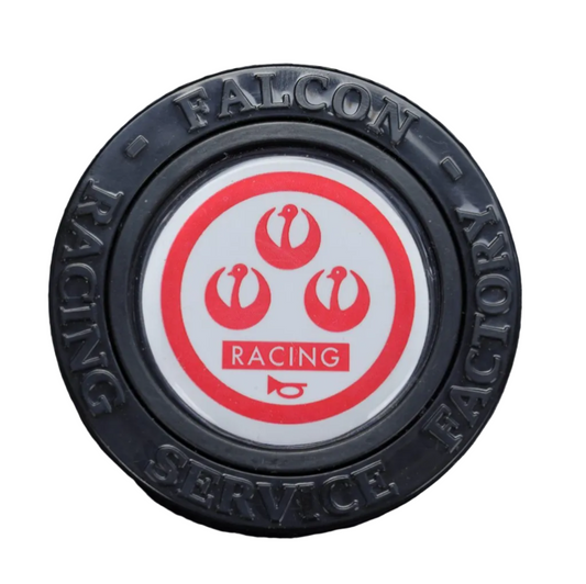 Round black rubber mat with 'Falcon Racing' logo on a textured gray surface