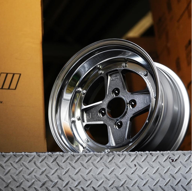 Metallic car rim on a textured surface with a cardboard box in the background